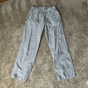 Randiga byxor i blått och vitt - Snygga randiga byxor i blått och vitt med elastisk midja. Perfekta för en avslappnad stil. Byxorna har en rak passform och är tillverkade i ett lätt och bekvämt material.