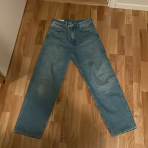 Blå jeans från H&M - Säljer ett par blå jeans från H&M med loose fit. De har en klassisk femficksdesign och är tillverkade i ett slitstarkt denimtyg. Perfekta för en avslappnad stil. Skriv vid minsta frågor.