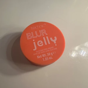 Technic Blur Jelly Primer - Säljer en Technic Blur Jelly Primer som är silikonfri. Den kommer i en rund, orange burk med ett vitt lock. Perfekt för att skapa en jämn bas innan sminkapplicering.