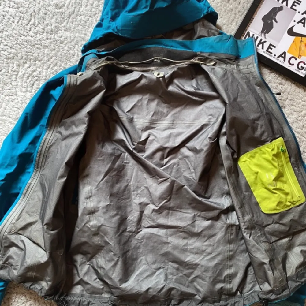 Säljer en blå vindjacka från Arc'teryx med huva och dragkedja. Jackan är tillverkad i Gore-Tex-material och har praktiska fickor med dragkedjor. Perfekt för utomhusaktiviteter och skyddar mot väder och vind. Pris går att diskutera, För fler bilder eller frågor så skriv till mig! . Takit.