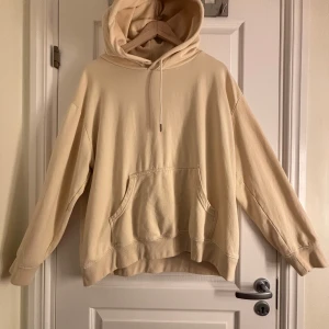 Beige hoodie från H&M - Säljer en beige hoodie från H&M Basics. Den har en klassisk känguruficka och justerbar huva med dragsko. Perfekt för en avslappnad stil. Passar bra till både jeans och mjukisbyxor.