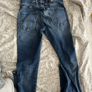 Blå jeans från Replay Anbass hyperflex - Snygga blå jeans från Replay, modell Anbass. De har en slim fit passform och är tillverkade i jeansmaterial. Byxorna har klassiska fem fickor och en dragkedja med knapp framtill. Perfekta för en stilren look.   