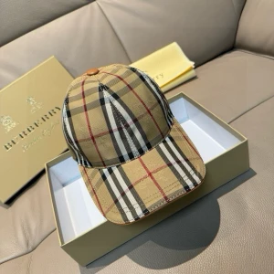 Rutig keps från Burberry - Snygg rutig keps från Burberry i klassiskt mönster med beige, svart och röd färg. Kepsen har en justerbar rem baktill i brunt läder för perfekt passform. Perfekt accessoar för en stilren look.