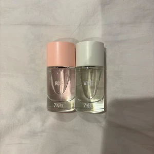 Dubbla parfymer från Zara - Två parfymer från Zara, en med rosa kork och en med vit kork. Den rosa heter 'Rose' och den vita 'White'. Flaskorna är genomskinliga och visar vätskan inuti. Perfekt för den som vill ha variation i sin doftgarderob.