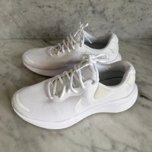 Vita sneakers från Nike - Snygga vita sneakers från Nike med en stilren design. Skorna har snörning och en bekväm sula som ger bra stöd. Perfekta för både träning och vardag.