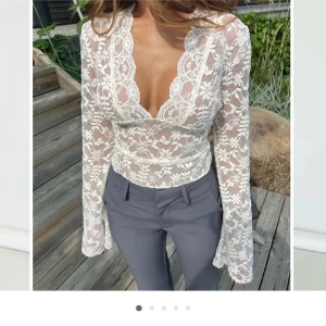 Vit spetsblus med v-ringning - Elegant vit spetsblus med v-ringning och långa ärmar. Blusen har ett vackert blommigt mönster och är perfekt för en stilfull look. Aldrig använd, i storlek s/m💕