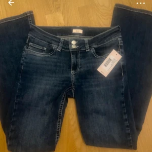 Mörkblå bootcut jeans från Nelly - Snygga mörkblå bootcut jeans från Nelly med låg midja. Jeansen har dekorativa sömmar på bakfickorna och en klassisk femficksdesign. Perfekta för en avslappnad stil. Helt nya!!