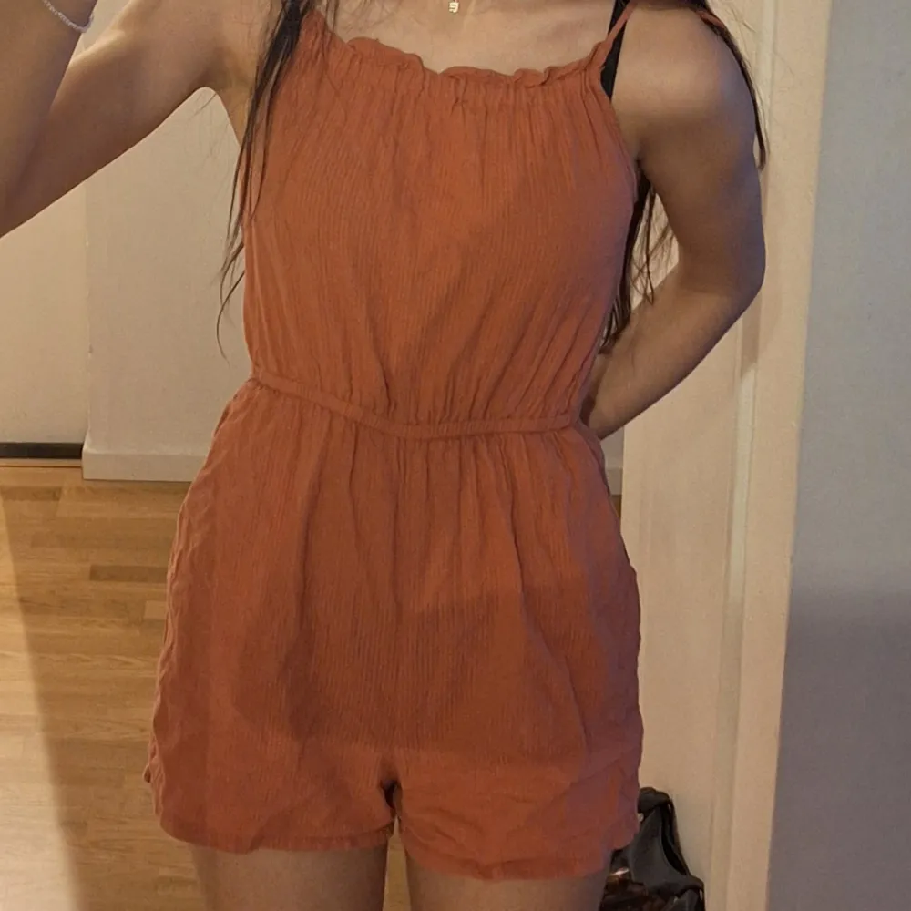 Säljer en snygg orangeaktig ärmlös jumpsuit med smala axelband. Är i storlek 146. Mekot.