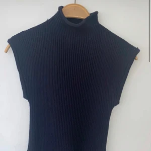 Marin blå ribbad ärmlös topp - Snygg marin blå ribbad topp med hög krage och ärmlös design. Perfekt för lager-på-lager eller att bära som den är. Enkel och stilren för en modern look.