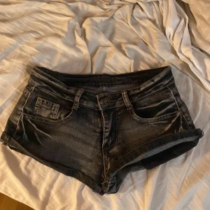Svarta jeansshorts - Snygga svarta jeansshorts med klassisk femficksdesign. Perfekta för en avslappnad sommarlook. De har knappar bak på fickorna för extra stilpoäng. Dem är köpta på pop boutiqe och är vintage! Skriv för mer bilder om det behövs 🫶💕