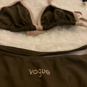 Mörk grön bikini från Vogue - Snygg mörkgrön bikini från Vogue (från 90-talet, var mammas) med beigea kantdetaljer. Överdelen har trekantsform och knytband för justerbar passform. Perfekt för en dag på stranden eller vid poolen.