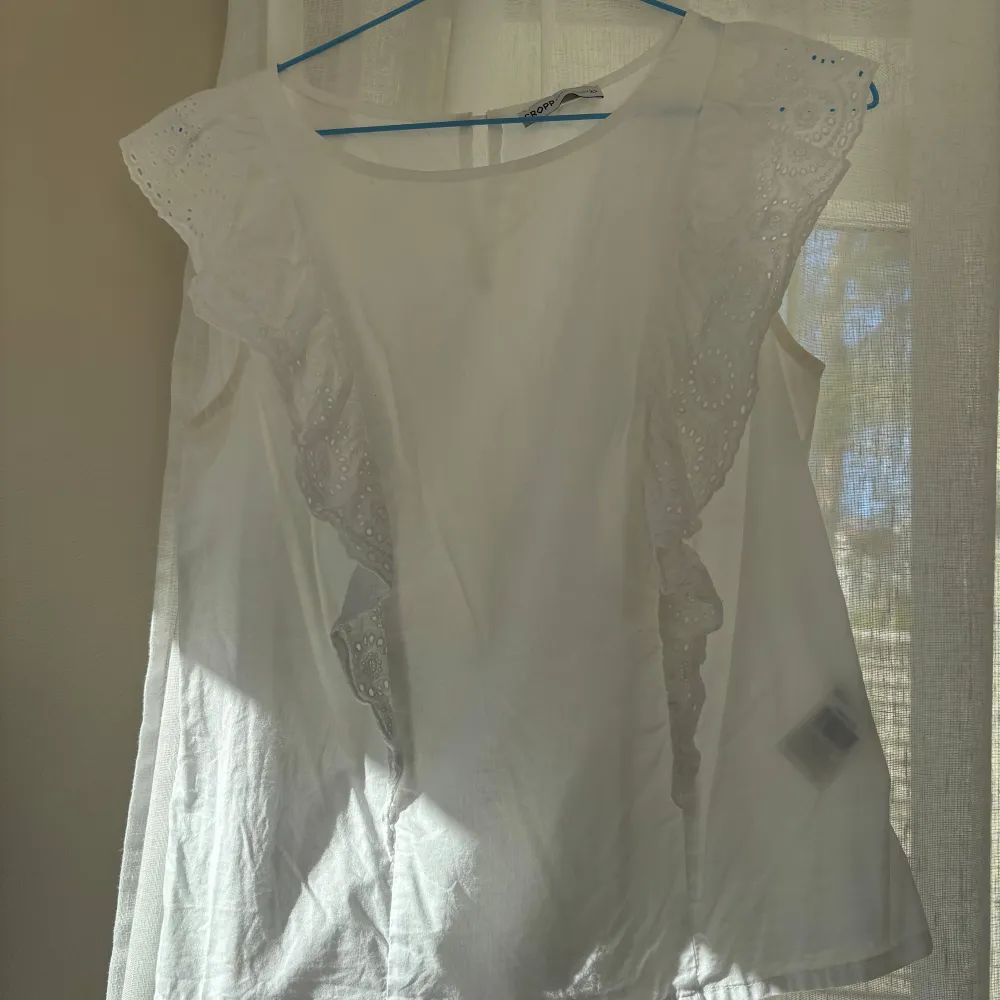 Säljer en söt vit ärmlös blus från Cropp med vackra spetsdetaljer längs axlarna. Perfekt för varma sommardagar eller som ett stilrent lager under en kavaj. Blusen har en luftig passform och rund halsringning. ( har liten missfärgning vid armen, men inget som syns när man har den på sig). Puserot.