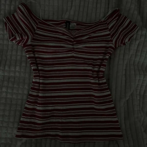 Randig offshoulder topp - Säljer en randig offshoulder topp i rött och vitt. Toppen har en smickrande passform med korta ärmar och en liten rynkdetalj framtill. Perfekt för en avslappnad stil. Den är helt ny använde den knappt❤️