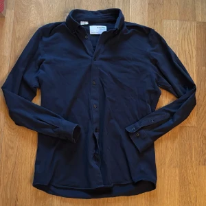 Mörkblå skjorta från Selected Homme - Säljer en stilren mörkblå skjorta från Selected Homme. Skjortan har en slim passform och är utrustad med knappar framtill. Perfekt för en elegant look.