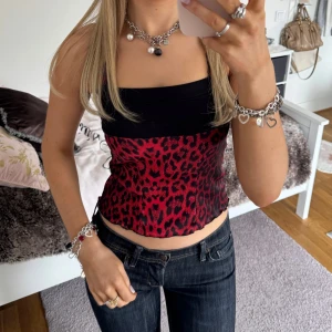Röd leopardmönstrad topp - Snygg röd leopardmönstrad korsettopp med svarta detaljer. Toppen har axelband och en tight passform som framhäver figuren. Perfekt för en kväll ute eller när du vill sticka ut lite extra. ⊹ jag är 173cm & stl S/36/28 för referens ⊹ läs POLICY (i gillade inlägg) innan köp ⊹ använd gärna ”Köp” ⊹ 