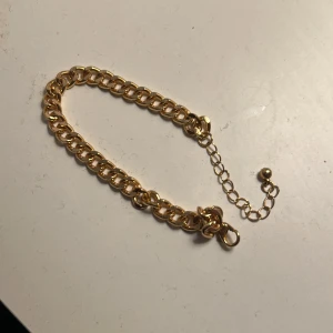 Guldarmband med kedjedesign - Snyggt guldarmband med en klassisk kedjedesign. Armbandet har en justerbar kedja med en liten kula i slutet för enkel anpassning av storleken. Perfekt för att ge en elegant touch till din stil.
