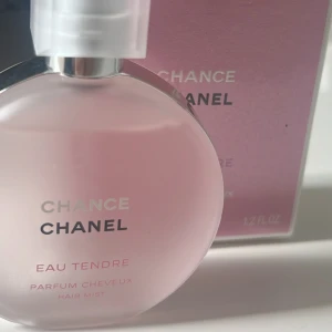 Chanel Chance Eau Tendre Hårmist - Chanel Chance Eau Tendre hårmist i en elegant rund flaska med rosa ton. Perfekt för att ge håret en fräsch och blommig doft. Flaskan har en stilren design med ett genomskinligt lock och den ikoniska Chanel-loggan.