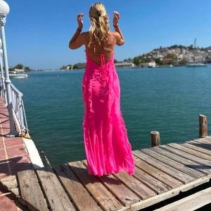 Rosa långklänning - Säljer en fantastisk rosa långklänning med volangdetaljer och öppen rygg. Perfekt för sommarens festligheter. Endast använd en gäng och den är kemtvättad så helt ren! Den är verkligen otrolig!!😍😍Den är storlek 42 men jag har sytt in den till storlek 36/38 som jag är!