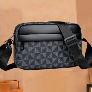 Svart och grå axelväska med geometriskt mönster - Snygg axelväska i svart och grått med ett coolt geometriskt mönster. Väskan har en justerbar axelrem och en praktisk dragkedja framtill. Perfekt för att bära dina nödvändigheter med stil.