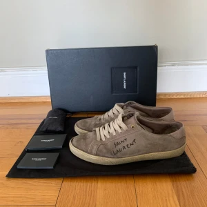 Beige skor Saint Laurent - Säljer ett par exklusiva beiga sneakers från saint Laurent. Skorna är i väl använt skick men har fortfarande lite mer att ge. (Nypris ca 7000) mitt pris  499. Skorna är storlek 41 men är lite stora i storleken. Skornas defekter finns visade på bilderna