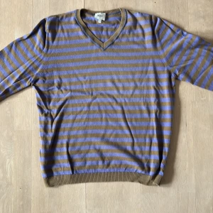 Cerruti tröja från 1881 Sorlek L - Säljer en randig tröja från 1881 i brunt och lila. Tröjan har en v-ringad hals och långa ärmar. Perfekt för en avslappnad stil.