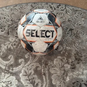 Fotboll från Select - Säljer en fotboll från Select med svart, vit och orange design. Bollen har märkningen 'FIFA Quality Pro' vilket garanterar hög kvalitet för professionellt spel. Perfekt för fotbollsträning eller matcher.