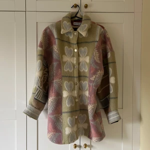 Jacka från Rave Review - Säljer en unik och stilren jacka från Raye Review med ett vackert mönster i beige, rosa och grått. Jackan har långa ärmar och knappar framtill. Perfekt för att ge din outfit en färgglad touch!