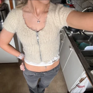 Beige kofta med dragkedja - Säljer en beige ribbad kofta med korta ärmar och dragkedja framtill. Den här superskönt material och är inte alls stickig! Perfekt för en bekväm look. 