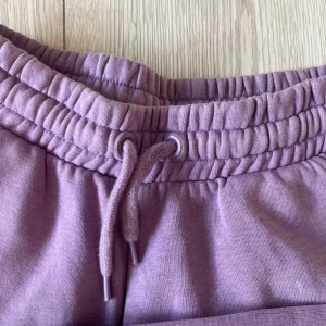 Lila mjukisbyxor med snörning - Säljer ett par lila mjukisbyxor med elastisk midja och snörning. Perfekta för en avslappnad stil. Byxorna har en bekväm passform och är gjorda i mjukt material.🩷🩷