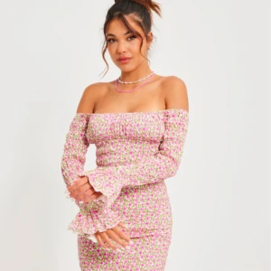 Blommig offshoulder klänning från Nelly - Säljer en söt blommig offshoulder klänning från Nelly i rosa och grönt. Klänningen har långa ärmar med volangdetaljer och en smickrande tight passform. Perfekt för sommarens alla tillfällen! 🌸 Helt ny med prislappen kvar 