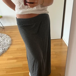 Mörkgrå långkjol  - Säljer en enkel och stilren mörkgrå långkjol med normal passform. Kjolen är rak i modellen och har resår i midjan för extra komfort. Perfekt för dig som gillar en avslappnad och minimalistisk stil.