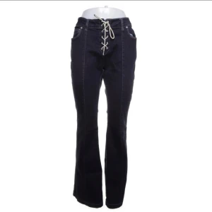 Jeans med snörning fram - Snygga mörkblå jeans med bootcut passform och unik snörning framtill i midjan. markerade sömmar. Storlek 31 Kan skicka mer bilder på hur de sitter om så önskas 