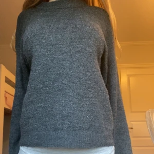 Mörkgrå stickad tröja - Mysig mörkgrå stickad tröja med lång ärm och rak passform. Perfekt för kyligare dagar och enkel att matcha med olika outfits. Klassisk och stilren design utan synliga detaljer eller mönster.