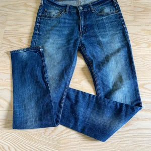Blå jeansbyxor från Acne Studios - Säljer ett par klassiska blå jeans från Acne Studios i modellen Ace Stretch Vintage. Jeansen har fem fickor, normal passform och raka ben. Perfekta för dig som gillar stilrena och tidlösa jeans. Storlek 32/32. Säljer då jag har växt ur dem