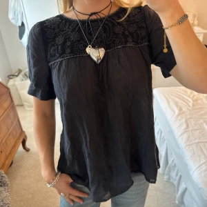 Kortärmad svart blus  - Svart kortärmad blus med blommiga detaljer från Twist & Tango🪻🪻🖤 Har tappat knappen där bak, men går enkelt att sy tbx