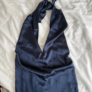  halternecktopp  - Säljer en marinblå halternecktopp från Bik Bok i glansigt material. Toppen har knyt i nacken och smockad rygg. 