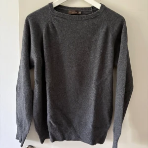 Grå ulltröja från Oscar Jacobson - Klassisk grå tröja från Oscar Jacobson i mjuk ull. Rund halsringning och ribbade muddar vid ärmslut och nederkant. Perfekt för lager-på-lager och enkel att matcha med olika outfits.