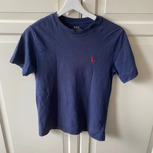 Blå t-shirt från Polo Ralph Lauren - Säljer en klassisk blå t-shirt från Polo Ralph Lauren med röd broderad logga vid bröstet. Är i storlek M men sitter som en S. Mycket bra skick. Hör av er vid intresse !!