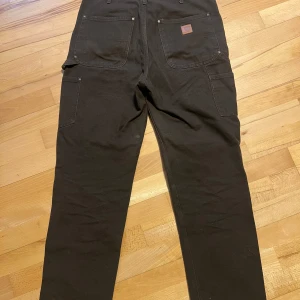 Carhartt double knee mörkbruna jeans  - Carhartt double knee jeans i brunt, syns inte superbra på bild men dom är bruna. Storlek 28W 32L. ”Loose original fit” enligt carhartt, dom är relaxed/loose fit