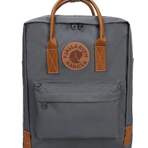 Grå ryggsäck från Fjällräven Kånken - Säljer en klassisk grå Fjällräven Kånken ryggsäck med bruna detaljer och handtag. Väskan har en stor ytterficka med dragkedja och det ikoniska runda märket framtill. Perfekt för skola eller utflykter. 20L