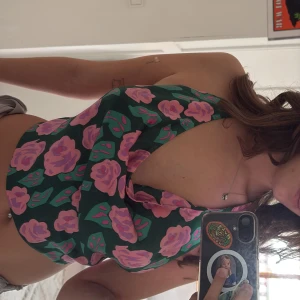 Grön blommig halterneck-top från TEN11 - Säljer en snygg grön halterneck-top från TEN11 med rosa och lila blommor. Toppen har en croppad passform och knyts i nacken och ryggen. Perfekt för sommardagar när du vill sticka ut lite extra!