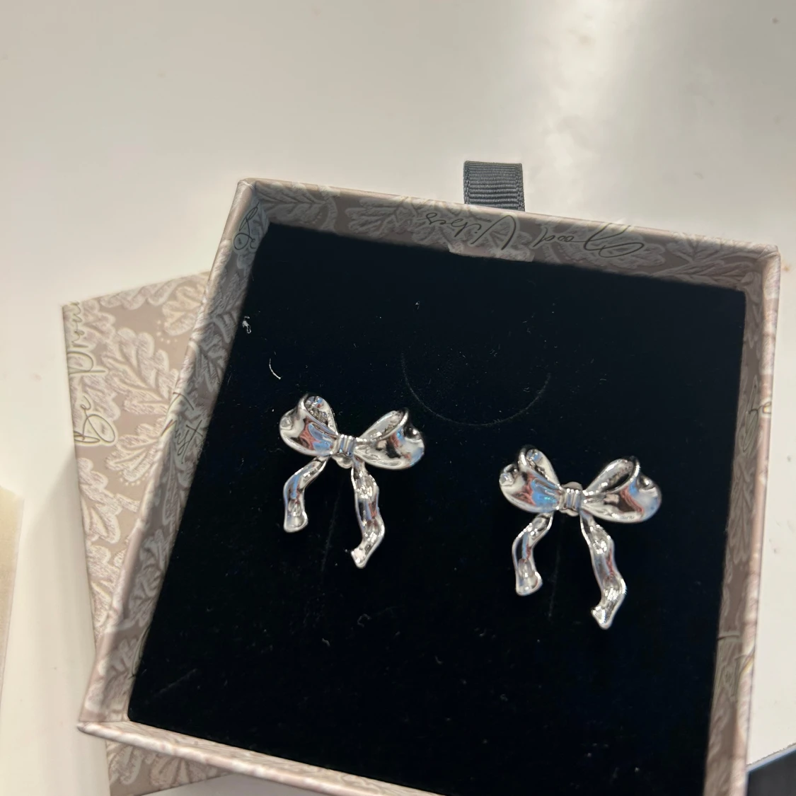 Söta silverfärgade rosettörhängen