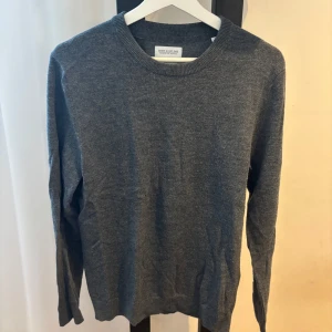 Grå merinoulltröja från These Glory Days - Säljer en stilren grå tröja från These Glory Days i mjuk merinoull. Klassisk rund halsringning och långärmad modell, perfekt för lager-på-lager eller som den är. Enkel och tidlös design som passar till det mesta.