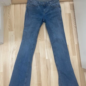 Blå bootcut jeans från ZARA - Säljer ett par klassiska blå bootcut jeans från ZARA. Jeansen har fem fickor, normal passform upptill och utsvängda ben. Tillverkade i denim med snygg tvätt och traditionella detaljer som dragkedja och knapp. Använd max fem gånger jeansen är i ett jättebra skick
