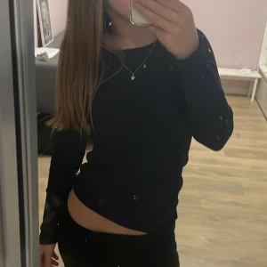 Mörkblå långärmad tröja - Säljer en mörkblå långärmad topp med tre silvriga dekorativa knappar på ena axeln. Perfekt att styla till olika outfits.