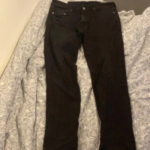 Svarta jeansbyxor från H&M - Snygga svarta jeansbyxor från H&M i straight modell med regular fit. Perfekta för en stilren look. Tillverkade i Bangladesh.