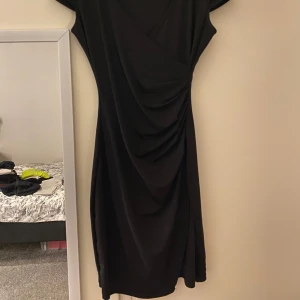 Svart omlottklänning från Chiara Forthi - Säljer en svart omlottklänning från Chiara Forthi Milano i storlek S. Klänningen har korta ärmar, draperad effekt framtill och en elegant v-ringning. Använd fåtal gånger, bra stretch🌸