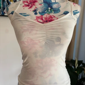 Vit croppad linnetopp med rynkdetalj - Säljer en vit croppad linnetopp med smala axelband och snygg rynkdetalj framtill. Toppen är figurnära och har en enkel, stilren design som passar perfekt till sommaren.