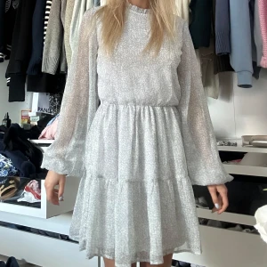 Ljusblommig volangklänning från NLY Trend - Superfin ljusblå klänning med blommigt mönster från NLY Trend. Klänningen har volangdetaljer, långärmade voluminösa ärmar och öppen rygg med knapp i nacken. Tillverkad i polyester med mjukt innerfoder. Perfekt nu till sommar!!