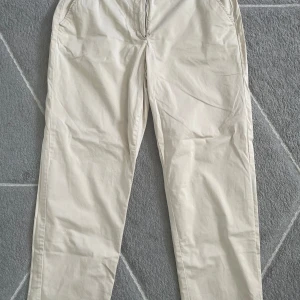 Beiga chinos - Snygga beiga chinos med normal passform och raka ben. Byxorna har knapp i midjan samt bälteshällor. Perfekta för en stilren och avslappnad look.